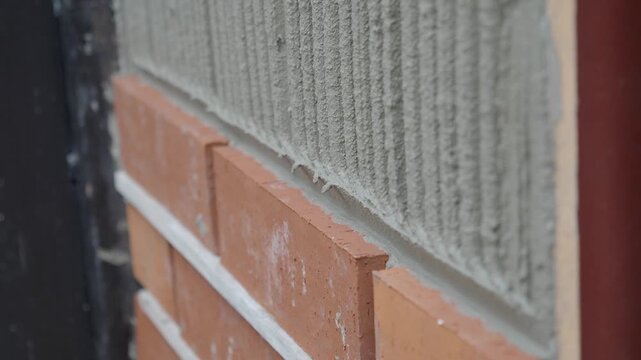A bricklayer is seen applying mortar on a wall as part of the building construction process