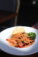 Homemade Spaghetti spicy seafood with prawn and squid on white dish.