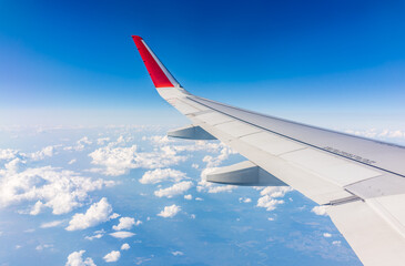 Fototapeta premium View from the airplane window at a beautiful cloudy sky and the airplane wing
