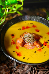 pumpkin cream soup with salmon and microgreens macro photo