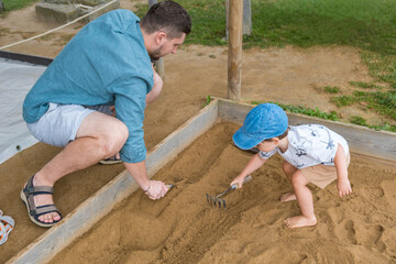 Dad and son in the sandbox at the archaeological park excavating with a rake
