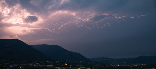 Panorama of a long branched lightning bolt over the Italian Alps, north of Verona, Italy