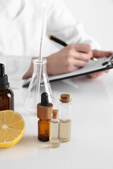 Aromatherapy product. Scientist developing essential oils at white table in laboratory, closeup
