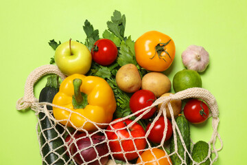 Delivery of vegetarian products. String bag with different vegetables and fruits on green background, top view