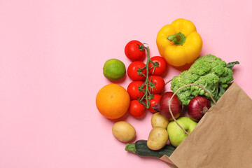Delivery of vegetarian products. Paper bag with different vegetables and fruits on pink background, top view. Space for text