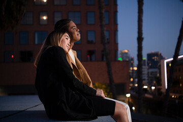 Multi racial couple snuggling embracing on urban rooftop at nigh