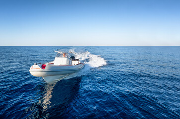 Front view of a sports RIB boat cruising with high speed over the blue sea, with copy space