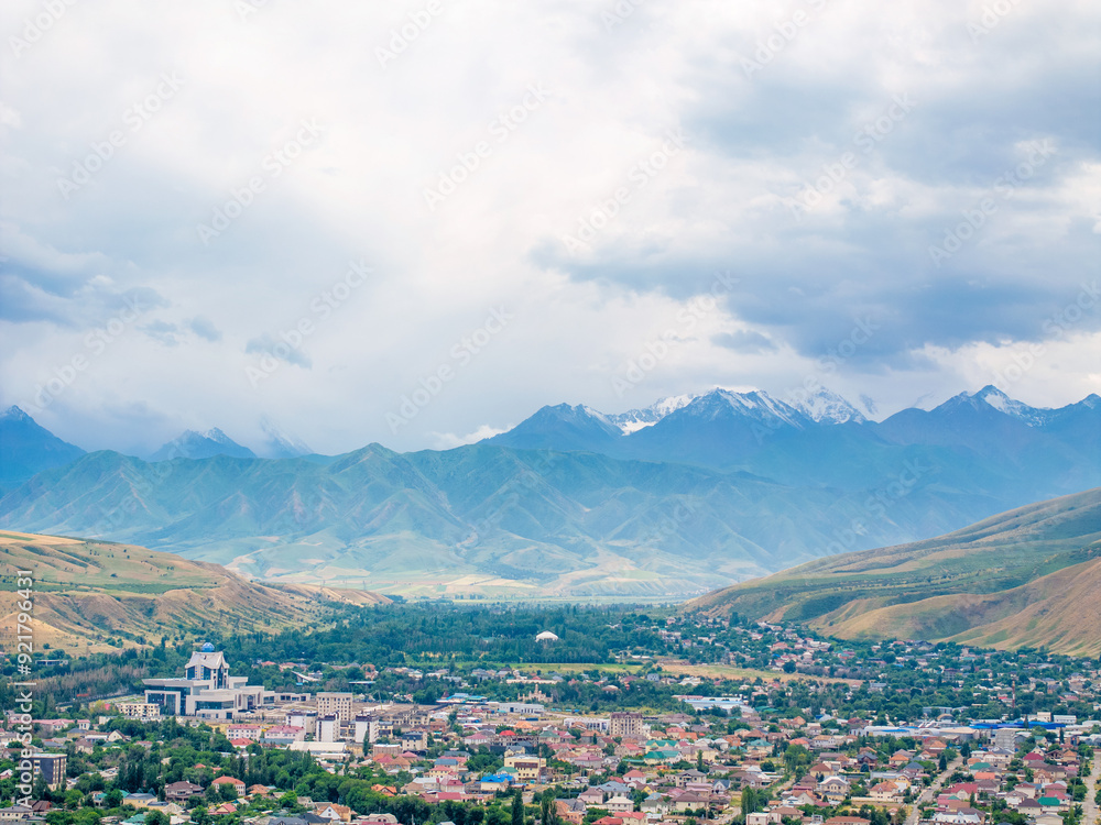 Wall mural drone view of the town and landscape with snow-capped mountains and hills. beautiful clouds over the