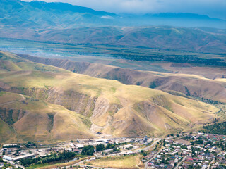 Drone view of a landscape with mountains and hills near a village. Beautiful clouds over the...