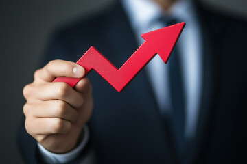 Businessman holding a red upwards graph arrow in hand arrow to show success from progress and growth of turnover and profit