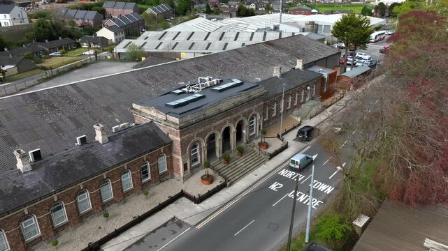 Monaghan Town, County Monaghan, Ireland, April 2024. Drone orbits counter clockwise as buses cross in front of the old Railway Station building heading to town centre.