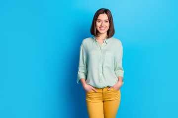 Portrait of confident lovely cheerful girl with stylish hair wear teal shirt hold hands in pockets...