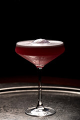 Cocktail in a martini glass on a dark background.