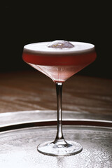 Cocktail in a martini glass on a dark background.