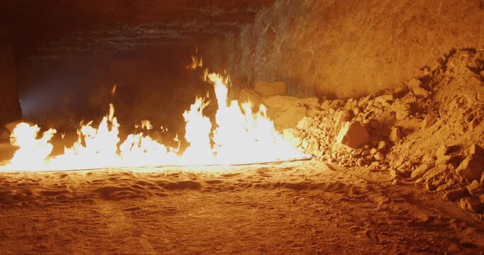 Flames rising inside of dark cave - wide, locked off shot