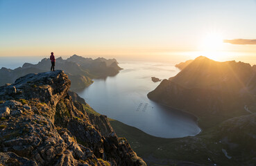 A woman enjoying the view and the midnightsun on the summit of Keipen, Senja.