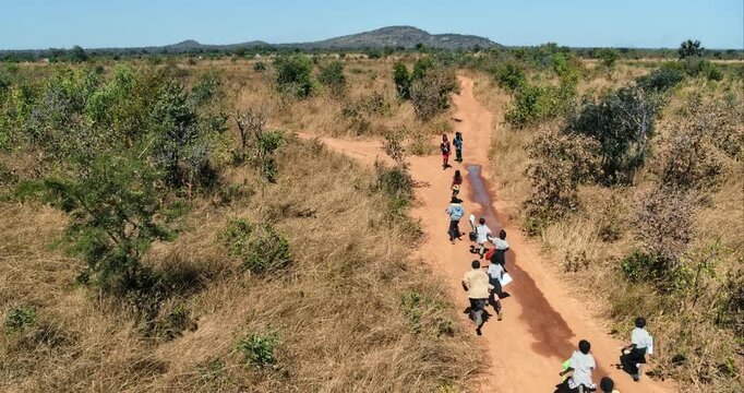 African kids running down dirt road - drone shot