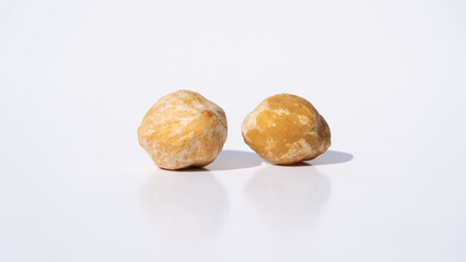 Two Dried Candlenut Seeds Cast Shadows on a White Background, Capturing Their Natural Texture