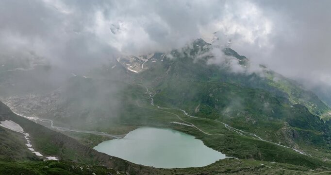 Susten Pass with Steinsee Lake in background, Swiss Alps. Aerial drone flying through clouds