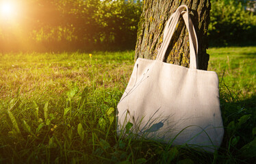White canvas tote bag mockup template with long handles among the green plant leaves outdoor