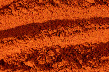Abstract terracotta striped background of scattered paprika seasoning