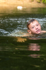 Fototapeta premium a boy bathes in a river in the summer on a hot day 