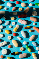 Colorful medicine, tablet, pills and capsules on blue background.