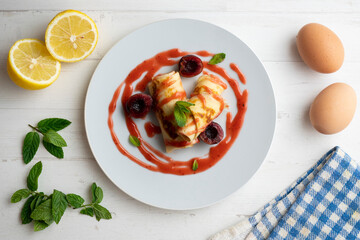Delicious rolls with crepe dough filled with cherry sauce. Table decorated with Christmas decorations.