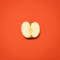Above, half apple and cut in studio for nutrition, healthy eating and gut health. Fresh fruit, divided or open on red background for fiber, digestion aid or antioxidants in diet with food for sharing