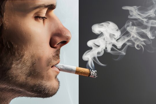 A close up of a rugged man smoking against a dark backdrop his expression fraught with thought