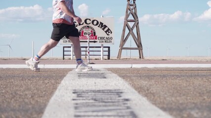 Man Walking Past Midpoint Sign Of Route 66 In Adrian, Texas. ground-level shot, slow motion