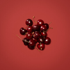 Above, cherries and bunch in studio for gut health, nutrition and sweet healthy snack. Fresh fruit, share and stems on red background for vitamin C, balanced diet or aid for digestion on mockup space