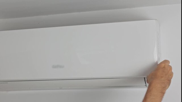 Cleaning technician opens the front cover from the wall-mounted air conditioner and removes the filter for cleaning
