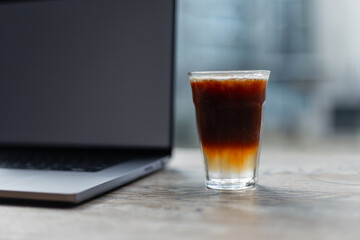 fragrant delicious fresh espresso tonic coffee stands on a wooden table with a laptop. Good morning and the start of work. Time to energy.