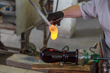 Worker of crystal glass manufacture is making drinkware.