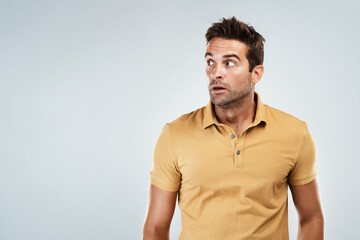 Scared, space and man with surprise in studio for gossip, fear and crazy drama on grey background....