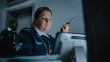 Female security officer or dispatch in uniform talks in walkie talkie, uses tablet computer and...