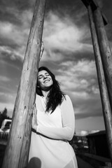 Fototapeta premium A woman in a white dress dances and poses on a swing high in the mountains at sunset. Freedom concept
