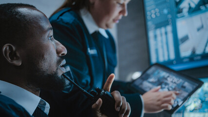 Multiethnic CCTV operators control security cameras on screens in monitoring center. Female worker...