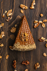 A piece of cake with walnuts on a dark wooden background.