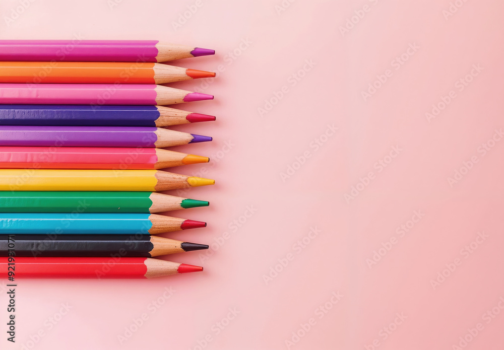 Poster row of colorful pencils is forming a gradient on a pink background with copy space
