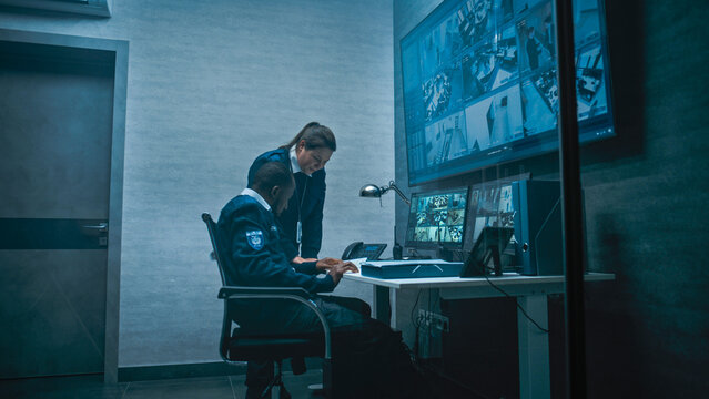 Female security worker have discussion with colleague in monitoring center, then leaves the office. African American CCTV operator works on computer with screens showing surveillance cameras footage.