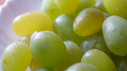 Close-up of large white grapes on a plate. Berries of white grapes laid out on a white plate