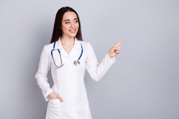 Photo of professional medical worker lady point finger empty space white coat isolated on grey...