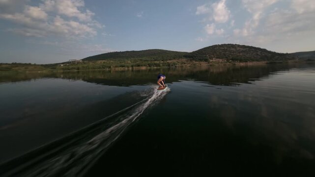 girl stands on hydrofoil. Calm smooth water on the lake early in the morning. High quality 4k footage fpv drone shot