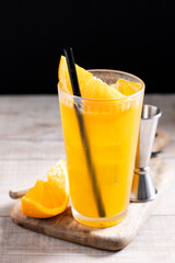 Orange vodka cocktail on wooden table and black background