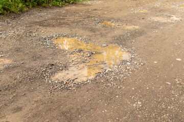 Pit on country road. A puddle in pit on the road