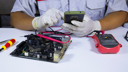 A technician use mobile phones to search for information about inspection and repair circuit board. A technician is searching for information on repairing an old electronic circuit board.