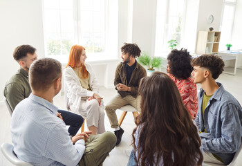 Diverse group of people team sits together in a circle, engaging in an active discussion and talking. Teamwork, communication, and collaboration highlight the importance of working during the meeting.