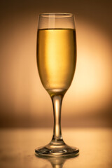 Vertical shot of a champagne glass brimming with bubbles, placed on the right against a gold-toned background. Captures the essence of Christmas and New Year's Eve celebrations.